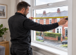 Installer measuring a replacement uPVC window inside a Manchester home